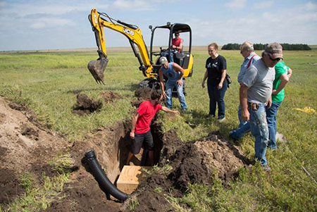 Heavy equipment excavating on pristine grasslands t place plastics into the ground for prairie dog relocation.